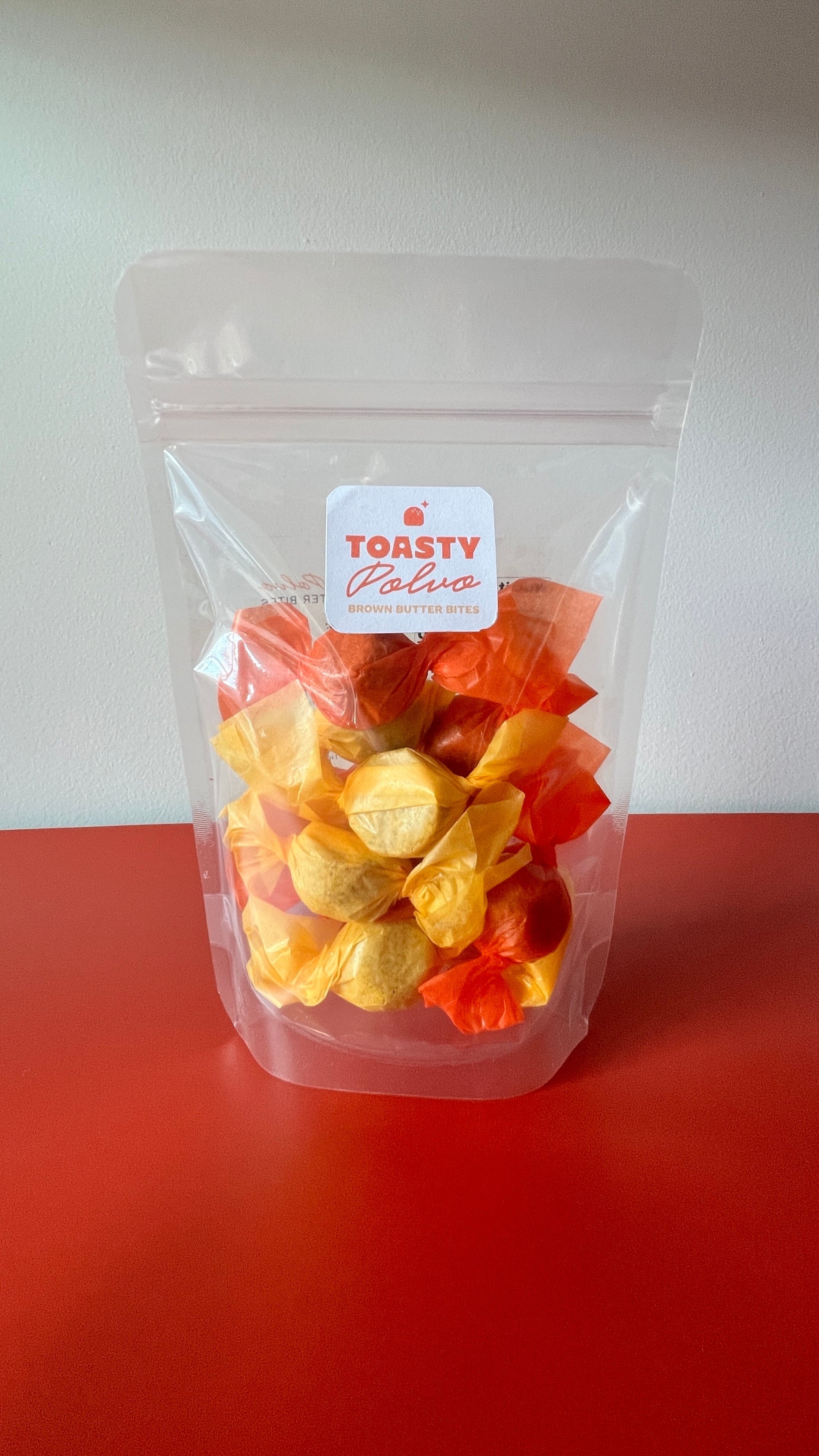 Clear bag of colorful candy with a 'Toasty Palate' label on a red surface.